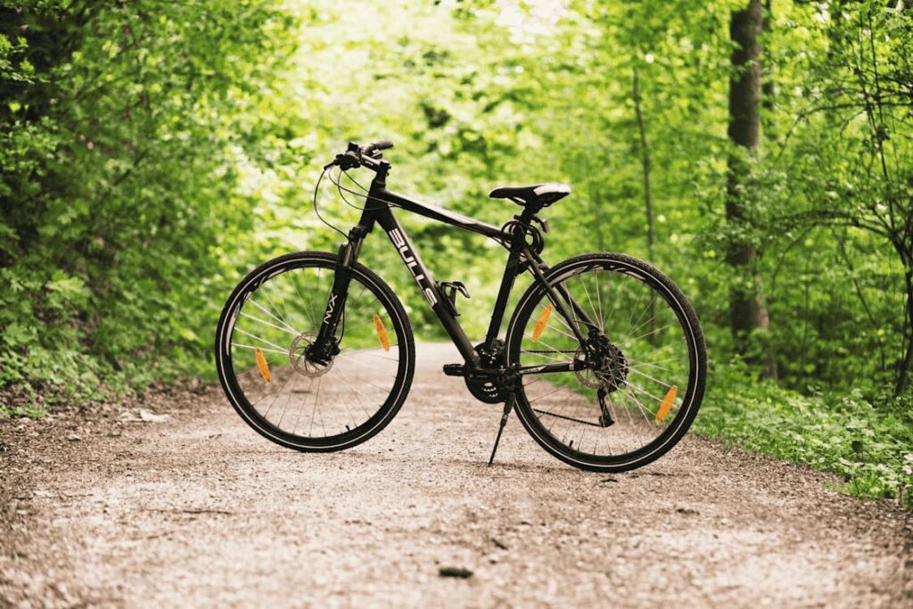 bicicleta de montana negra en sendero de tierra en medio de bosque verde
